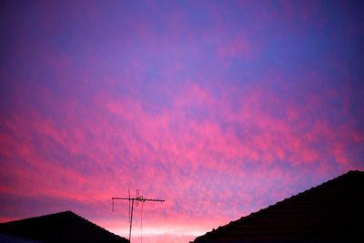 Low angle view of silhouette communications tower against sky at sunset