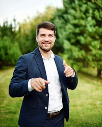 Portrait of businessman gesturing while standing at park