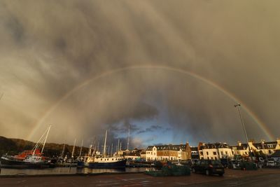 Sailboats moored on sea against rainbow in sky