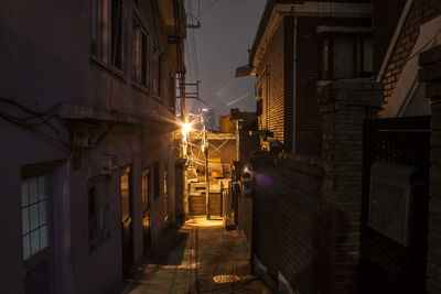 Illuminated street amidst buildings in city at night