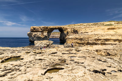 Rock formation by sea against sky