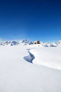 Snow covered landscape against clear blue sky