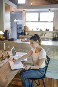 Woman working on laptop at dining table