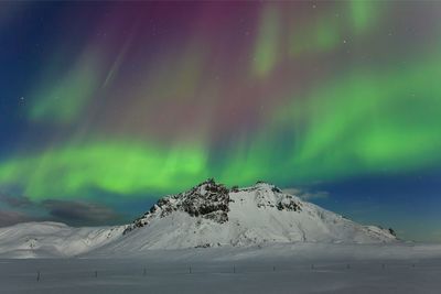 Scenic view of snowcapped mountain against sky at night