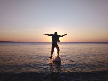 Full length of person in sea against sky during sunset