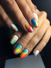 Cropped hands of mid adult woman with colorful nail polish