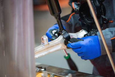 Close-up of manual worker repairing machinery while working in workshop