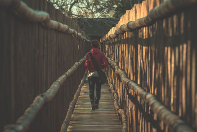 Rear view of woman walking on footbridge