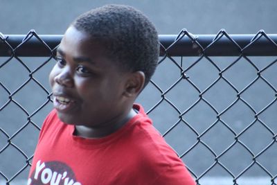 Close-up portrait of boy on chainlink fence