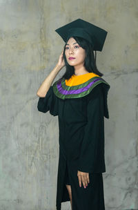 Portrait of a smiling young woman standing against wall