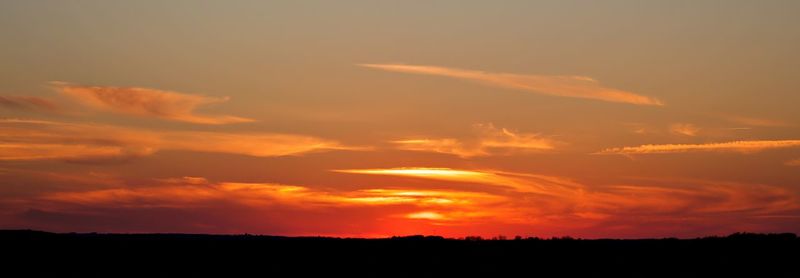 Silhouette landscape against dramatic sky during sunset