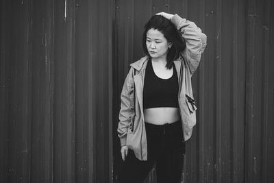 Portrait of young woman standing against corrugated iron