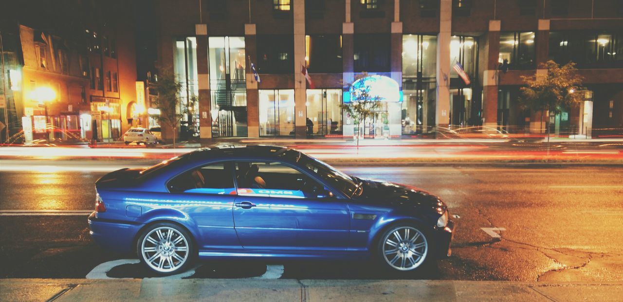 illuminated, night, building exterior, architecture, built structure, land vehicle, transportation, street, car, mode of transport, city, road, street light, city street, lighting equipment, stationary, headlight, parking, outdoors, building