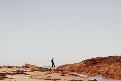 Man standing on rock against clear sky