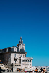 Group of people in front of building against clear blue sky