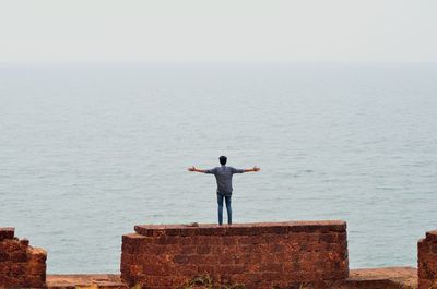 Rear view of a man overlooking calm sea