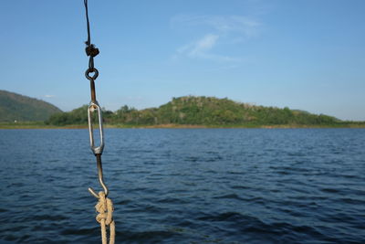 Close-up of rope hanging over river against sky