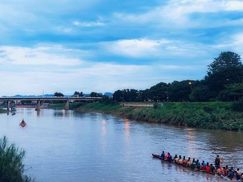 People on boat in river against sky