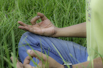 Midsection of man meditating while sitting by plants