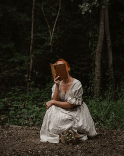 Rear view of woman sitting in forest