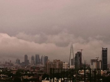 Modern cityscape against cloudy sky