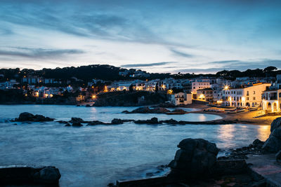 City by sea against sky at dusk