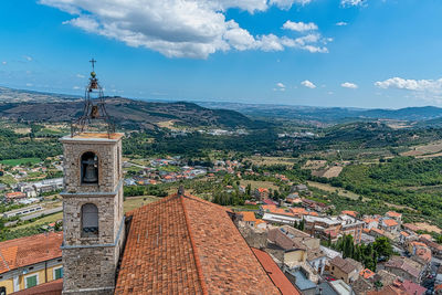 Aerial view of townscape with steeple and valley against sky. 