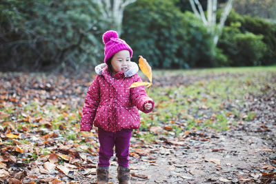 Full length of girl holding leaf in park