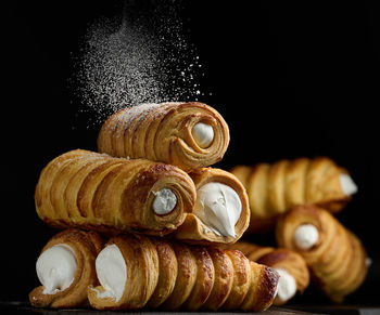 Baked tubules filled with whipped egg whites cream on a black wooden kitchen board