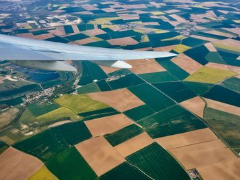 Cropped image of aircraft wing over patchwork landscape