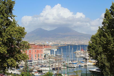 Sailboats in marina against cloudy sky