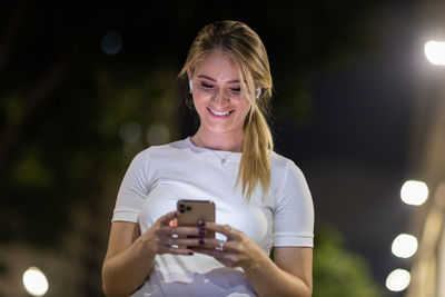 Woman using a smartphone at night time on the street. mobile phone, technology, urban .