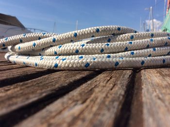 Close-up of rope tied on wood against blue sky