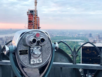 Close-up of coin-operated binoculars against cityscape