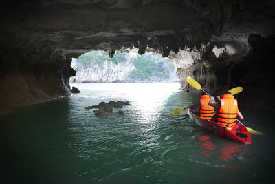 Rear view of people kayaking in cave