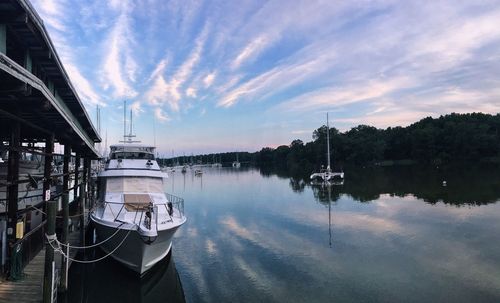 Boats moored at harbor against sky