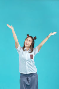 Portrait of young woman gesturing against blue background