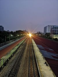 Railroad tracks in city against sky during sunset