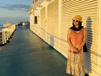 Young woman wearing sunglasses standing against built structure