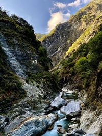 Scenic view of stream amidst rocks against sky