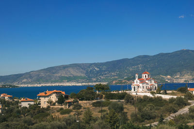 Scenic view of buildings and mountains against clear blue sky