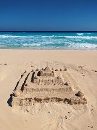 Sand castle at beach against clear sky