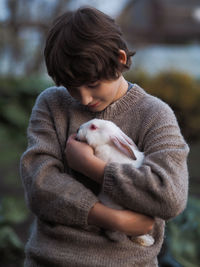 Boy holding rabbit outdoors