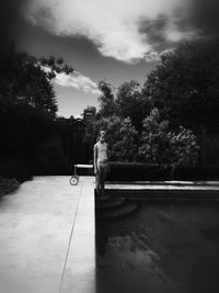 Man with umbrella against trees against sky