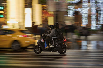 Blurred motion of people riding motorcycle on city street