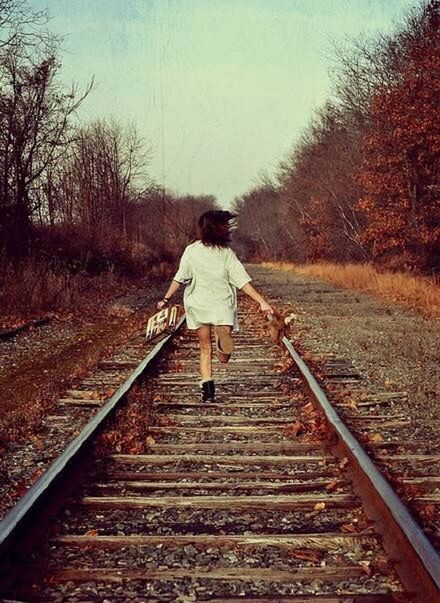 full length, railroad track, the way forward, lifestyles, casual clothing, tree, rail transportation, rear view, leisure activity, standing, clear sky, diminishing perspective, transportation, person, vanishing point, railing, young adult, front view