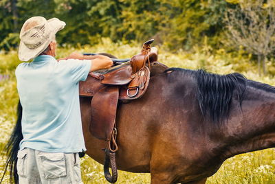 Man prepearing  horse for a ride