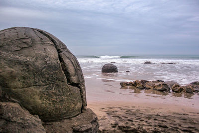 Scenic view of rocks on beach against sky