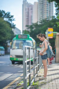 Woman standing on footpath in city