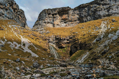 Scenic view of rocky mountains and waterfall against sky